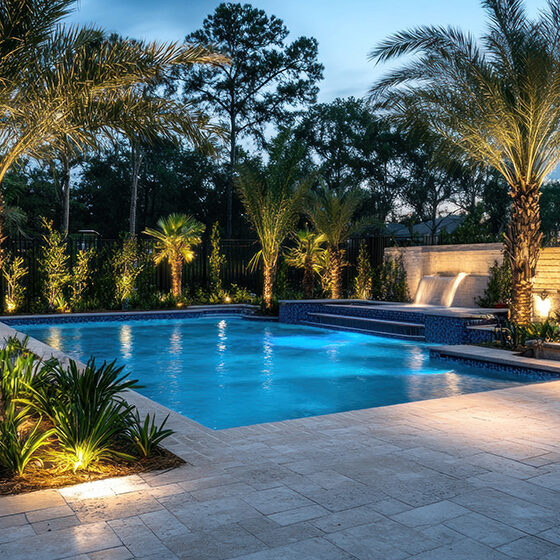 Illuminated Backyard Oasis With Pool And Waterfall Feature